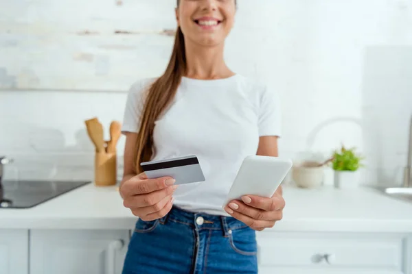 Selective focus of cheerful woman holding smartphone and credit card — Stock Photo