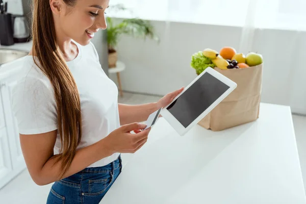 Jovem feliz segurando tablet digital com tela em branco e cartão de crédito — Fotografia de Stock