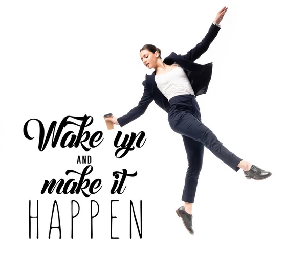 Young businesswoman holding coffee to go and dancing near wake up and make it happen lettering isolated on white — Stock Photo
