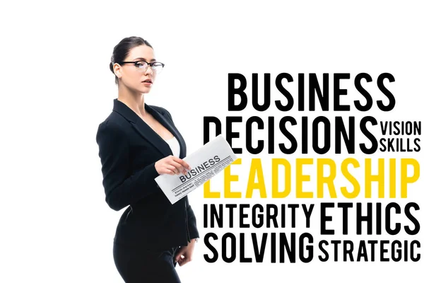 Confident businesswoman looking at camera and holding newspaper near business decisions, vision skills, leadership, integrity, ethics solving and strategic lettering isolated on white — Stock Photo