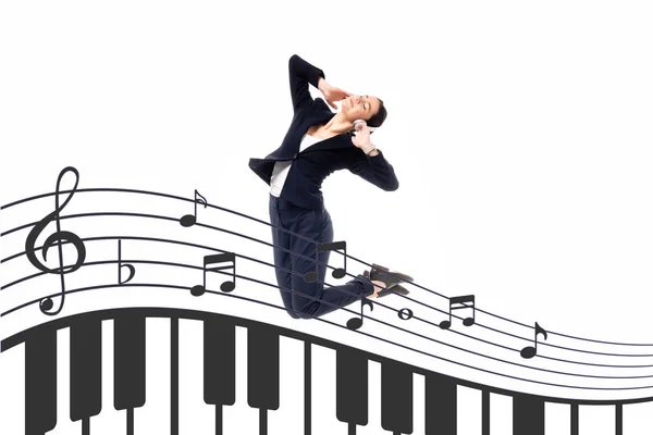 Молодая деловая женщина прыгает в танце рядом с иллюстрацией с нотами и клавишами фортепиано изолированы на белом — стоковое фото