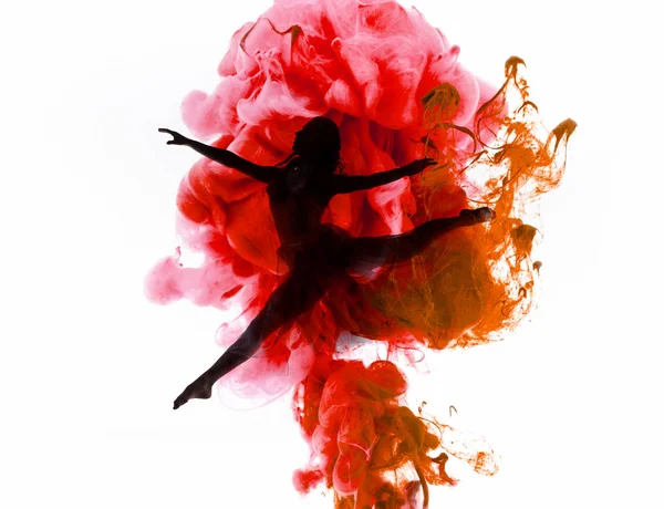 Silhouette di ballerina che balla in coloratissimi spruzzi di fumo rosa e rosso isolati su bianco — Foto stock