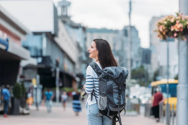 Вид сзади женщины с рюкзаком, идущей по улице — стоковое фото