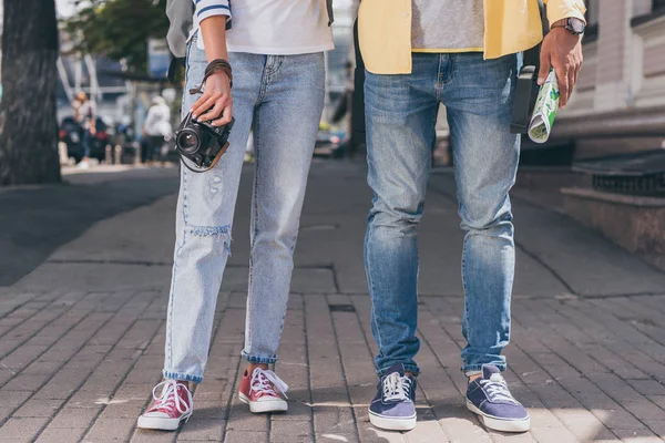 Partial view of tourists in jeans with digital camera and map — Stock Photo