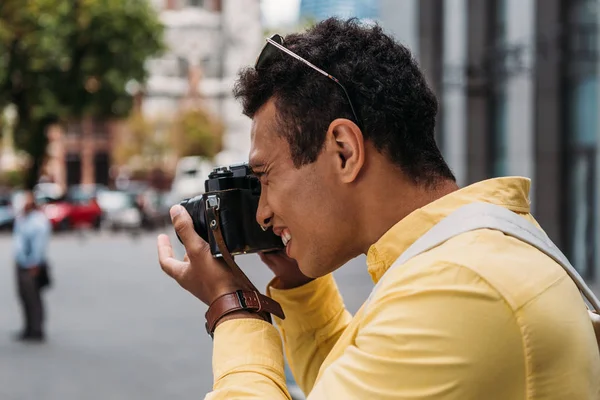 Hombre multiracial tomando fotos en cámara digital en la ciudad - foto de stock