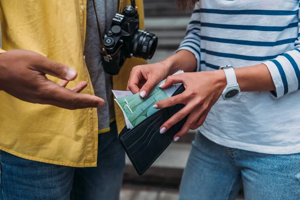 Vue recadrée de la femme vérifiant l'argent dans le portefeuille près d'un ami bi-racial — Photo de stock