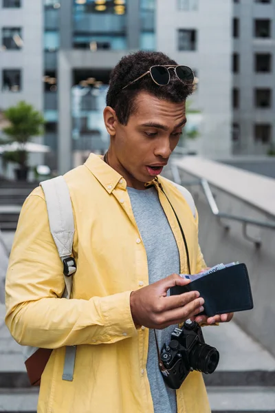 Surpris homme de race mixte regardant portefeuille avec de l'argent — Photo de stock