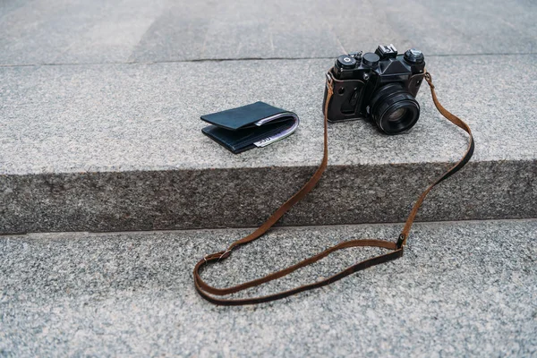 Portefeuille noir avec argent près de l'appareil photo numérique sur les escaliers — Photo de stock