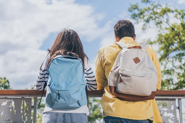 Back view of multicultural travelers standing with backpacks — Stock Photo
