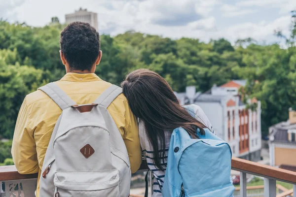 Vista trasera de turistas multiculturales de pie con mochilas - foto de stock