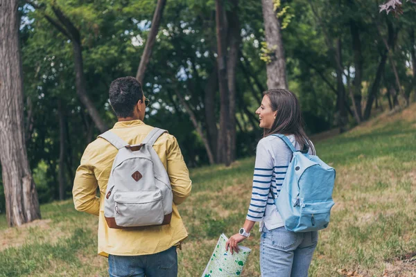 Vue arrière de la course mixte touriste debout près fille heureuse avec carte — Photo de stock