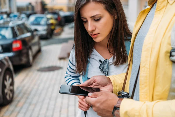 На снимке мужчина смешанной расы держит смартфон рядом с девушкой — стоковое фото
