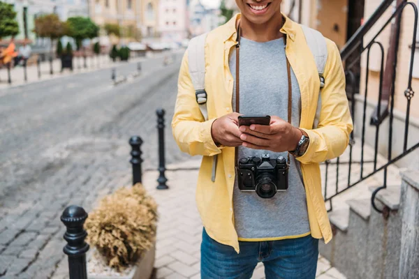 Обрезанный вид счастливого смешанного человека расы с помощью смартфона снаружи — стоковое фото