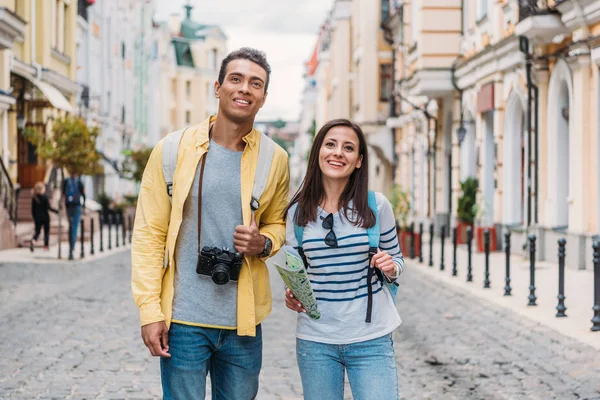 Счастливая женщина, стоящая с веселым двурасовым мужчиной на улице — стоковое фото