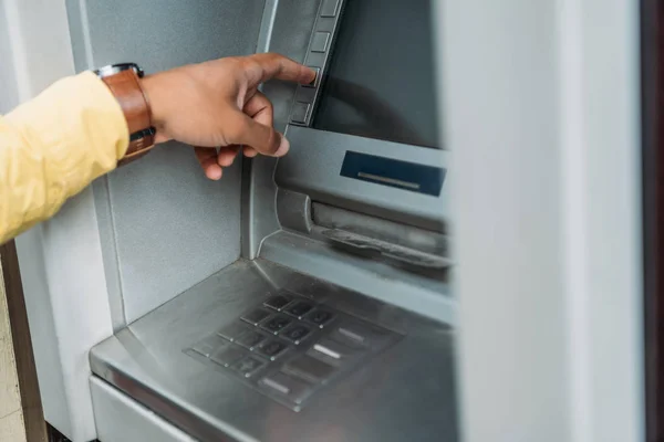 Обрезанный вид смешанной расы человек нажав кнопку на банкомат — стоковое фото