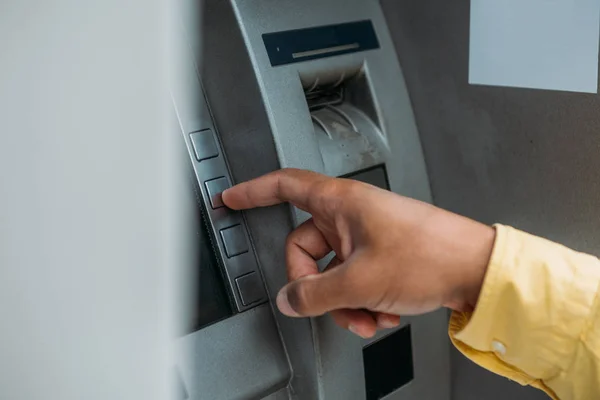 Vue recadrée de l'homme bi-racial appuyant sur le bouton sur la machine ATM — Photo de stock