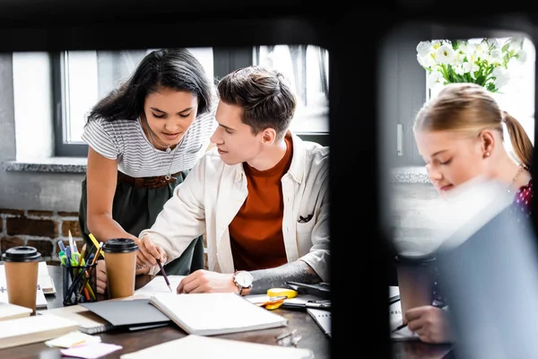Selective focus of attractive and handsome multiethnic friends studying in apartment — Stock Photo