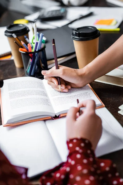 Cropped view of friends pointing with pencils at book — Stock Photo