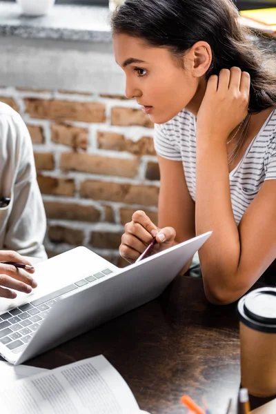 Vue recadrée d'étudiants multiethniques utilisant un ordinateur portable dans l'appartement — Photo de stock