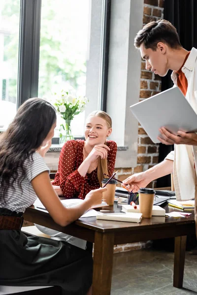 Multiethnic students smiling and looking at each other in apartment — Stock Photo