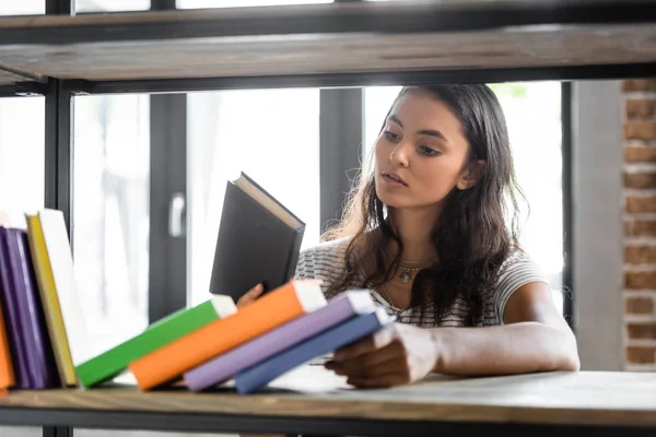 Selective focus of bi-racial student holding book in apartment — Stock Photo