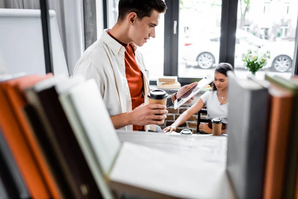 Selective focus of student holding paper cup and digital tablet — Stock Photo