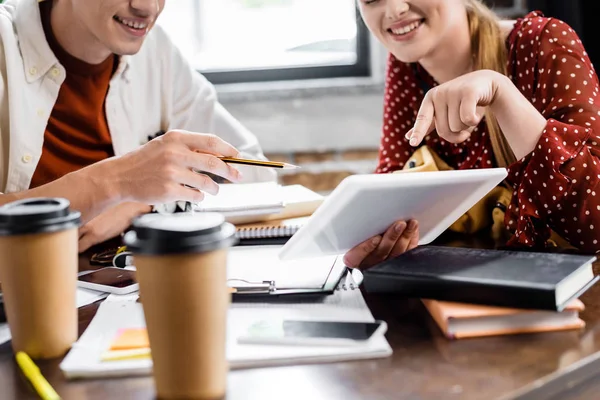 Cropped view of students smiling and looking at digital tablet in apartment — Stock Photo