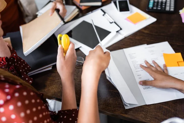 Cropped view of students holding stapler and papers in apartment — Stock Photo