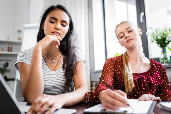 Enfoque selectivo de amigos multiculturales escribiendo y mirando hacia otro lado - foto de stock