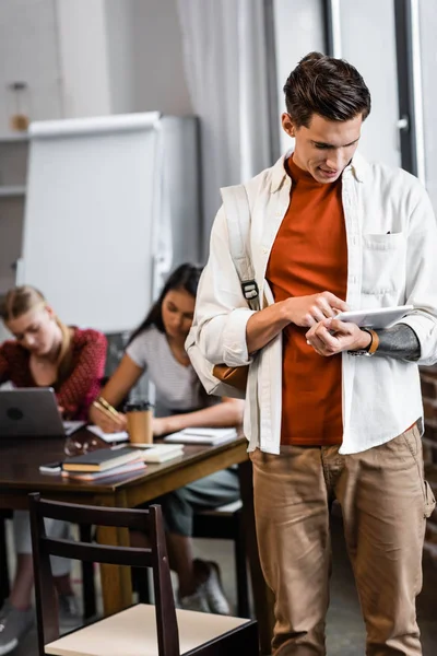 Beau étudiant en chemise en utilisant une tablette numérique dans l'appartement — Photo de stock