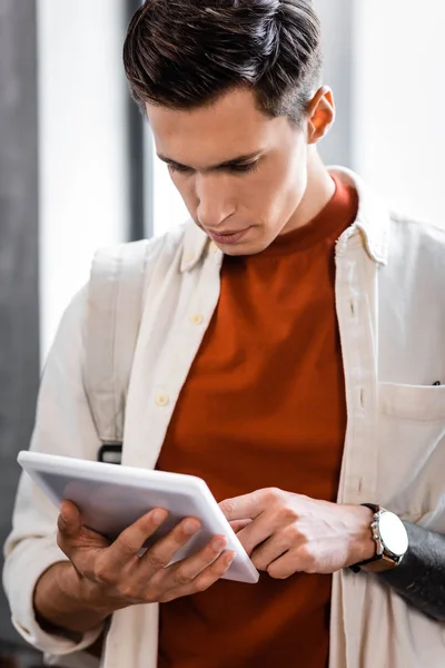 Handsome student in shirt using digital tablet in apartment — Stock Photo