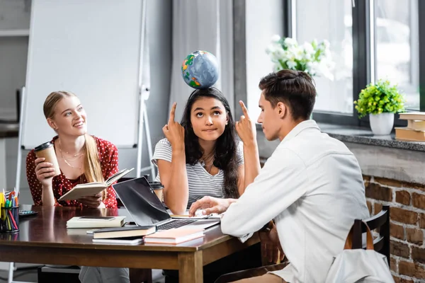 Étudiants multiculturels pointant du doigt le globe et tenant une tasse en papier — Photo de stock