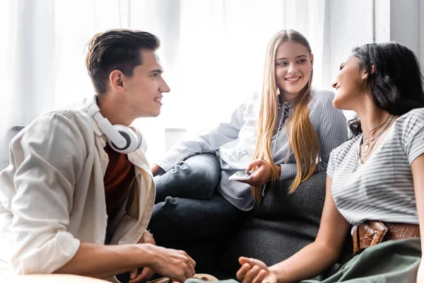 Handsome and attractive multicultural friends smiling and talking in apartment — Stock Photo