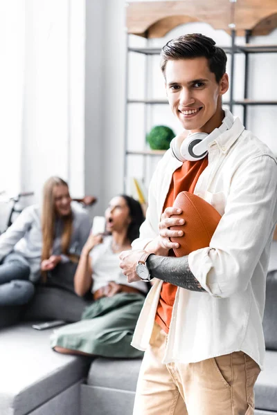 Selective focus of handsome man holding Rugby Ball in apartment — Stock Photo