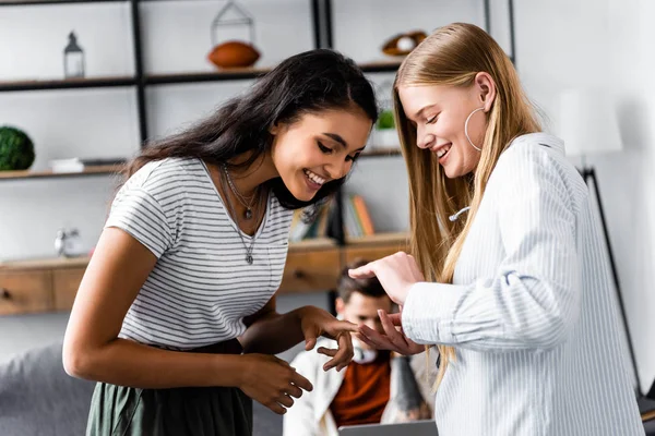 Focus selettivo di amici multiculturali che sorridono e parlano in appartamento — Foto stock