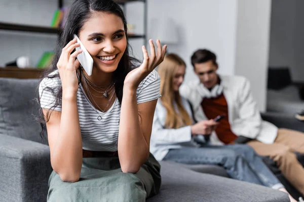 Selective focus of bi-racial woman smiling and talking on smartphone — Stock Photo