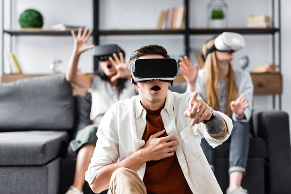 Selective focus of multicultural friends with virtual reality headsets sitting on sofa — Stock Photo