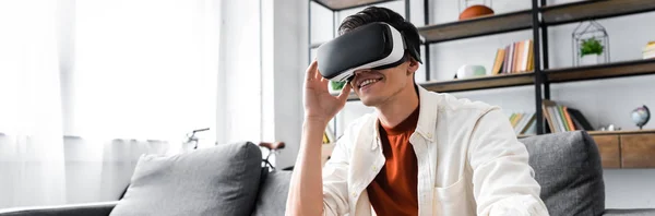 Panoramic shot of man with virtual reality headset in apartment — Stock Photo