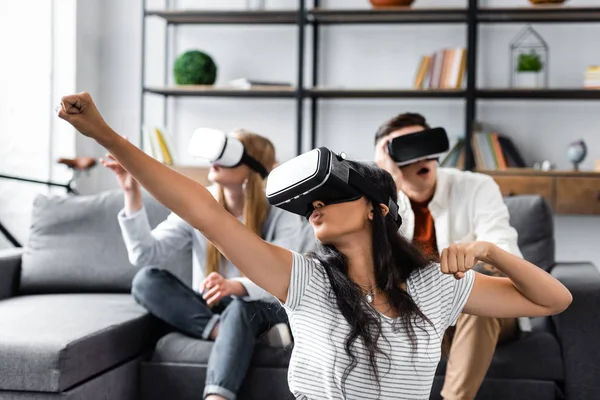 Foyer sélectif d'amis multiculturels avec des écouteurs de réalité virtuelle assis sur le canapé — Photo de stock