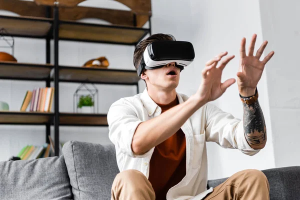 Homem emocional na camisa com fone de ouvido realidade virtual no apartamento — Fotografia de Stock