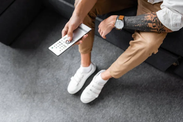 Cropped view of man holding remote controller in apartment — Stock Photo