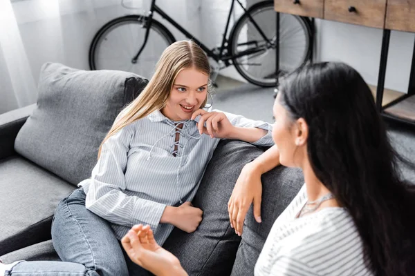 Enfoque selectivo de amigos multiculturales sonriendo y hablando en apartamento - foto de stock