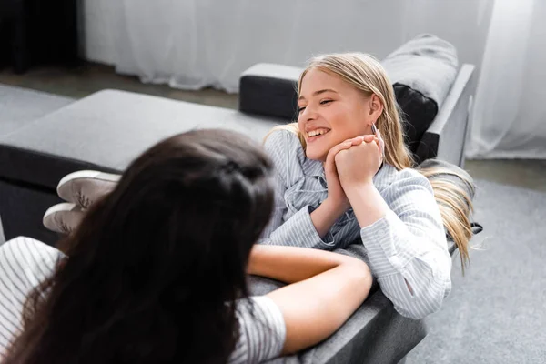 Selective focus of multicultural friends smiling and talking in apartment — Stock Photo
