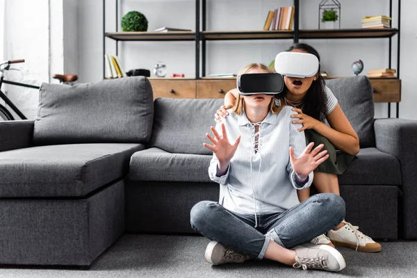 Multicultural friends with virtual reality headsets sitting on floor — Stock Photo