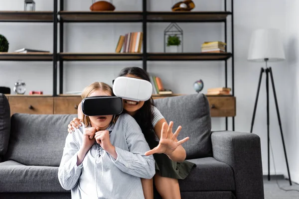 Amigos multiculturales sonrientes con auriculares de realidad virtual en el apartamento - foto de stock