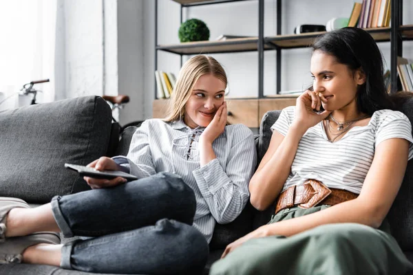 Multicultural friends holding remote controller and smiling in apartment — Stock Photo