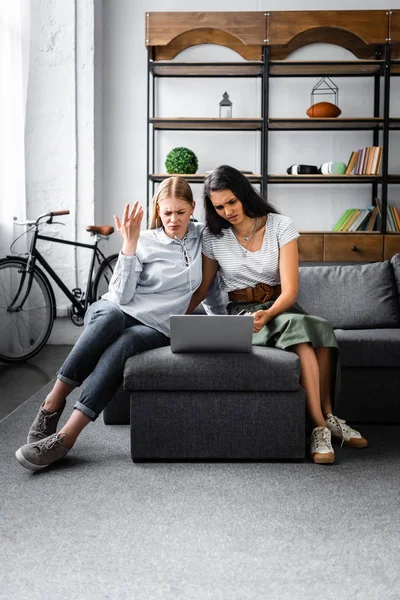 Amis multiculturels détenant une carte de crédit et utilisant un ordinateur portable dans l'appartement — Photo de stock