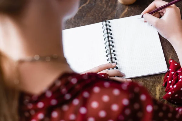 Selective focus of student writing in notebook with pencil in apartment — Stock Photo