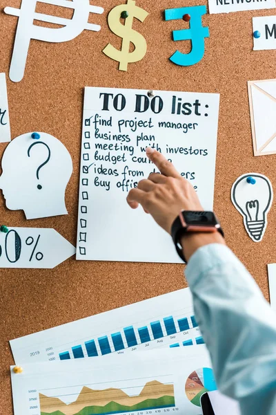 Ausgeschnittene Ansicht einer Geschäftsfrau, die mit dem Finger auf die To-do-Liste am Schwarzen Brett zeigt — Stockfoto