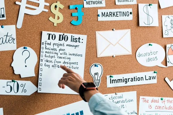Cropped view of businesswoman pointing with finger at to do list near lettering on notice board — Stock Photo